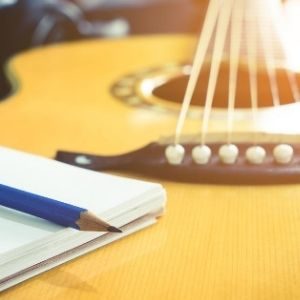 guitar, pen, paper, and flowers